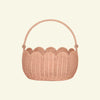 The Olli Ella Petal Basket in Seashell Pink features a scalloped design with a sturdy arched handle, crafted from natural wicker for rustic charm. Perfect for spring adventures or displaying against a neutral backdrop, it seamlessly combines practicality and style.