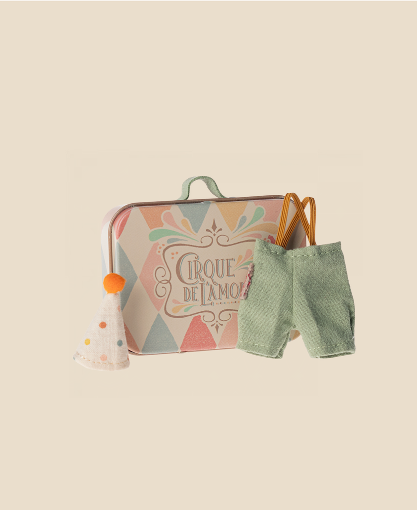 Maileg Little Sister With Clown Outfit: includes a pastel suitcase with "Cirque de l'Amour," green suspenders and pants, and a white party hat with orange pompom—perfectly sized for Maileg Mouse or Matchbox Mouse, shown on a beige background.