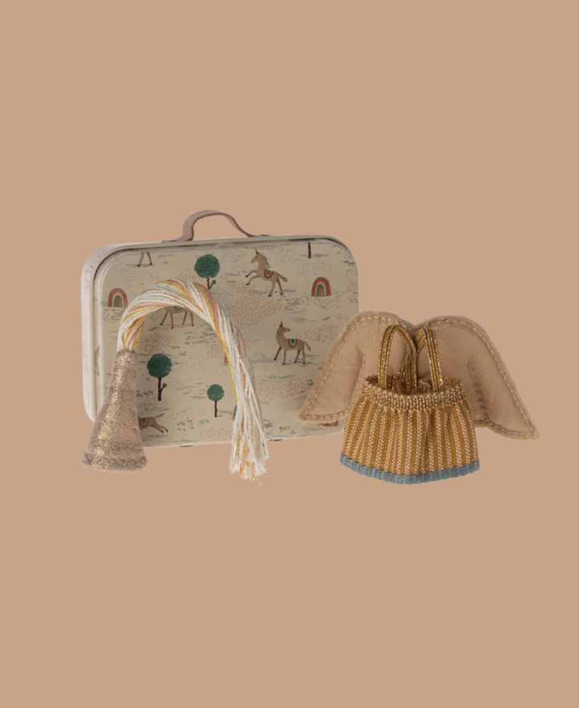 The Maileg Nursery Set With Mice features a small illustrated suitcase, gold party hat with tassels, fairy clothes, and a tiny golden basket with fabric angel wings, all displayed on a beige background.