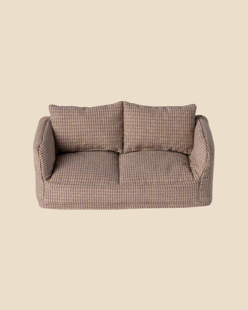 A small fabric sofa with a brown and gray checkered pattern sits beside a Maileg Living Room Set Soft Chair, featuring two cushions and armrests against a plain beige background.