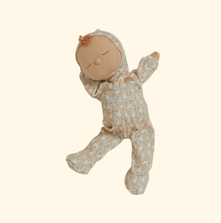 Meet the Olli Ella Dozy Dinkums - Custard - Garden Floral, a charming baby doll in a floral print sleeper with a cozy hood, sewn-on face, and tiny rainbow chest design—perfect for Easter as it rests serenely on a light background.