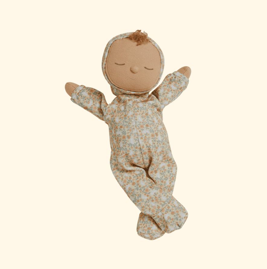 Introducing the Olli Ella Dozy Dinkums - Custard - Garden Floral: a fabric doll with a serene expression, ideal for Easter. This charming doll wears a garden floral hooded onesie, with gently outstretched arms and crossed legs against a simple, light backdrop.