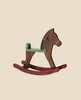 The Maileg Mouse Rocking Horse, featuring a vintage brown body, green seat, and red rockers, elegantly rests on a beige backdrop. Its classic design evokes nostalgic memories of timeless wooden toys. (Ships in one week).