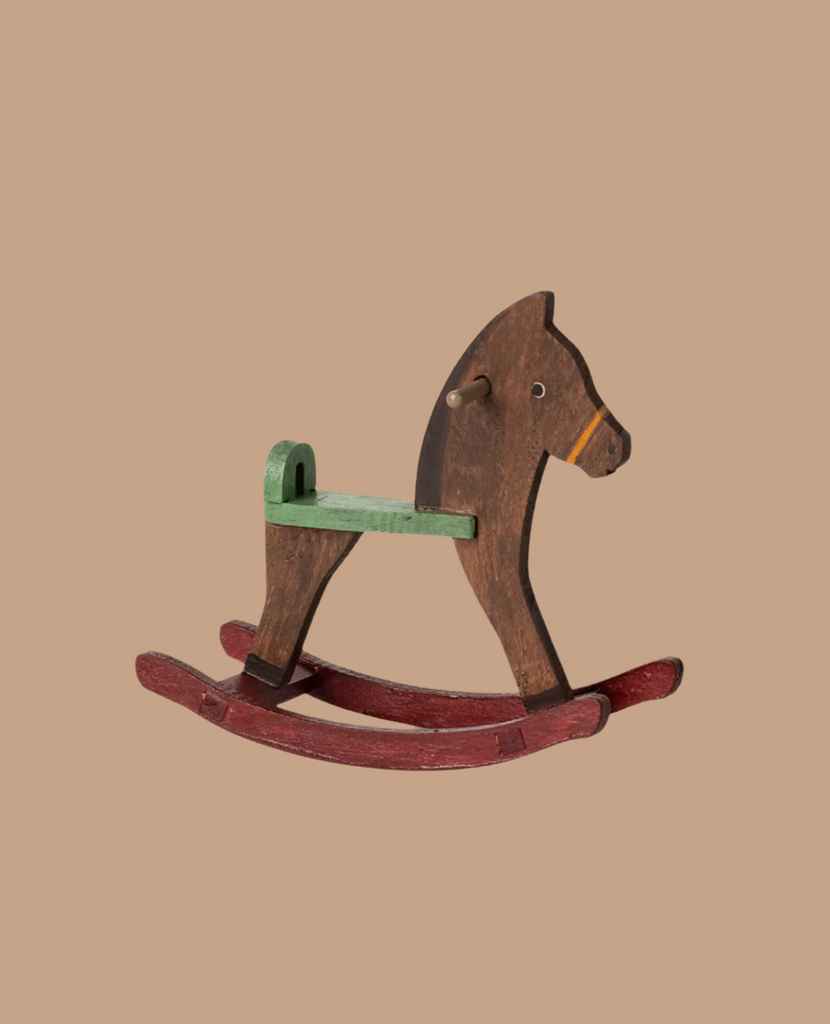 The Maileg Nursery Set features a vintage-style wooden rocking horse with a green seat, brown body, and red rockers, displayed against a plain beige background.