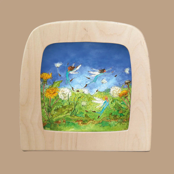 The "Silhouette Only - Dandelion for Toverlux Lamp" features whimsical fairies illuminated by the Magic Lamp, dancing over dandelions in a vivid blue sky, among translucent materials mimicking drifting seeds.