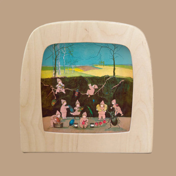 An enchanting illustration features small pink creatures engaged in whimsical activities, set against lush fields and hills. Captured as Magic Silhouettes in a Magic Window Frame, they create a magical scene titled "Silhouette Only - The Story of the Root Children silhouette - Winter for Toverlux Lamp.