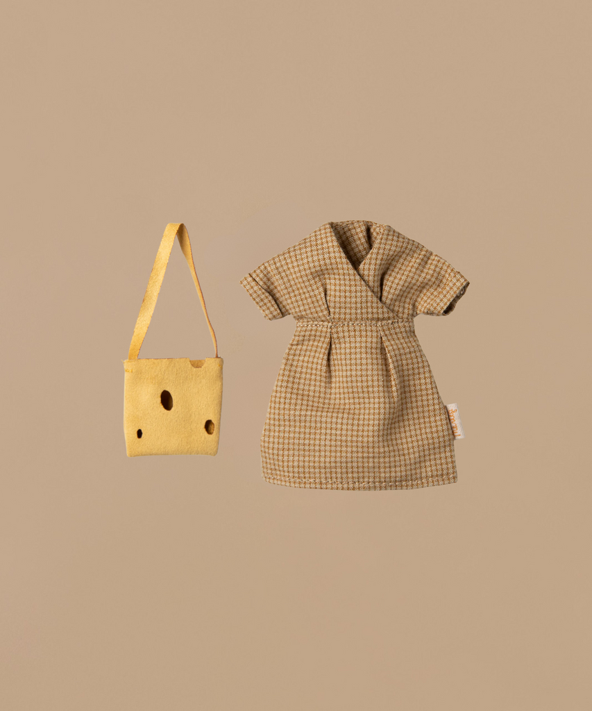 A small brown plaid dress lies next to a yellow tote bag with small holes, evoking an accessory for Maileg Mum Mouse - Light Brown (ships in one week). Both items rest on a plain beige background, crafting a charming scene.