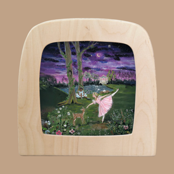 The "Moonlight Ballerina for Toverlux Lamp" features a framed silhouette of a ballerina in pink, dancing by a deer and rabbit near a pond. A crescent moon and stars cast an enchanting glow, with a house framed by trees and flowers in the background.