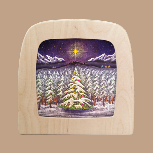 The "Silhouette Only - Christmas for Toverlux Lamp" features an enchanting snowy forest with a decorated Christmas tree, mountains, and camels under a starry sky. The light-colored wooden frame highlights the magical silhouettes cast by the bright star above.