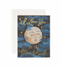 The To the Moon and Back Card features a moon with a face, blue swirls, and stars. “I Love You to the Moon & Back” is in metallic gold foil. The card is blank inside for your message and comes with an envelope.