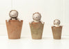 Three plush Harold The Hedgehog toys with gray bodies peek out of terracotta pots of varying sizes, ready for secret garden adventures against a white background. The smallest pot is on the right, and the largest is on the left.