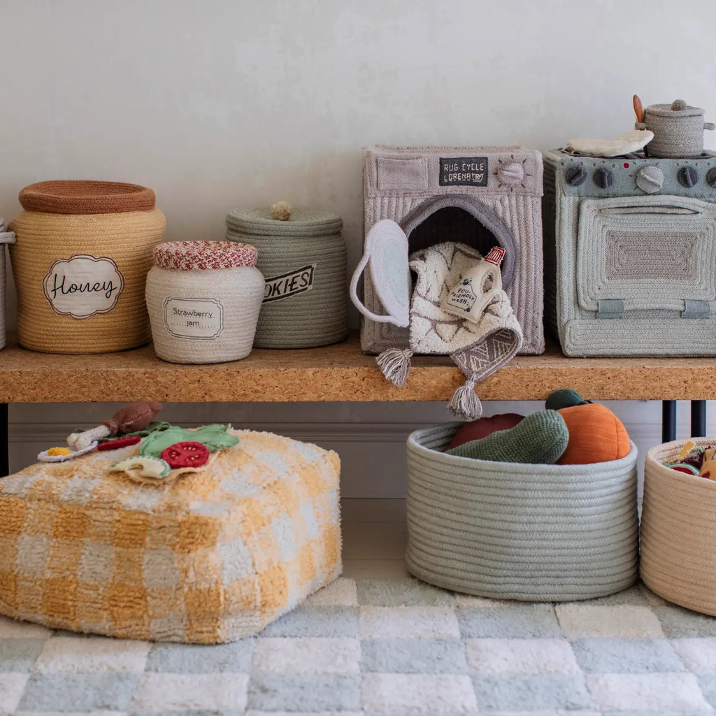 A variety of Strawberry Jam Jar Baskets containing household items like blankets and toys, labeled with tags such as "honey" and "cookies," arranged neatly along a shelf.