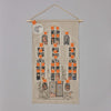 The Haunted House Advent Calendar is a fabric wall hanging featuring a spooky haunted house with 25 orange, numbered windows for a Halloween countdown. The house is adorned with ghostly figures, pumpkins, skeletons, and other eerie elements. A full moon illuminates the scene, revealing both tricks and treats as you count down to Halloween.