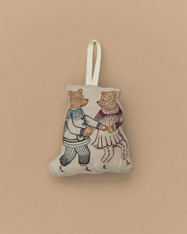 A charming Coral & Tusk Ice Skater Bears Ornament crafted from fabric, showcasing an embroidered design of two bears in vintage-style figure skating outfits. The bears are holding hands, and the ornament features a loop at the top for hanging. Its plain beige background makes it an ideal anniversary gift.