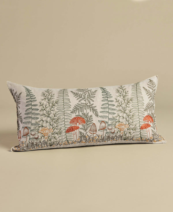 Rectangular decorative Coral & Tusk Mushrooms and Ferns Lumbar Pillow featuring a botanical and mushroom print on a cream background, displayed against an embroidered shade garden surface.