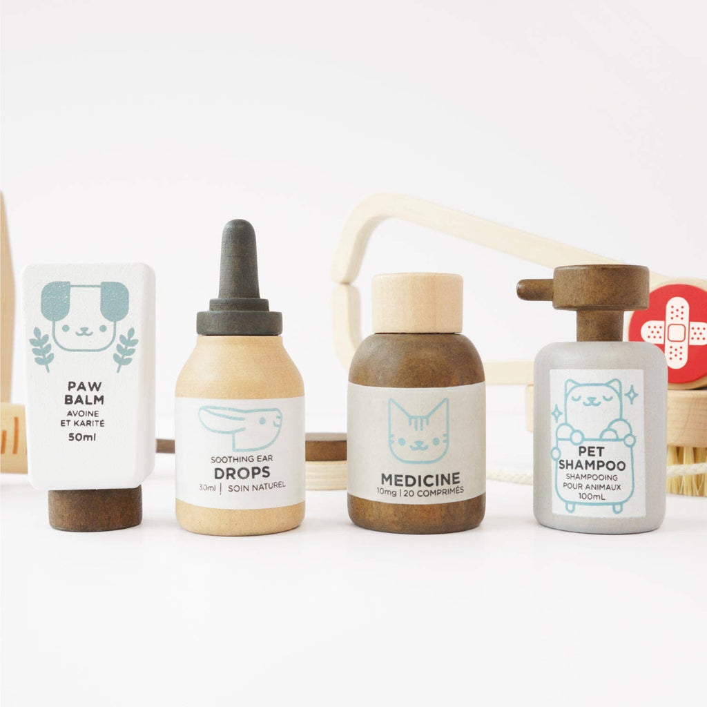Four toy bottles from the Pretend Play Animal Vet Set—paw balm, ear drops, medicine, and pet shampoo—feature pastel colors and cute animal designs on white, inspiring career role play fun for young vets.