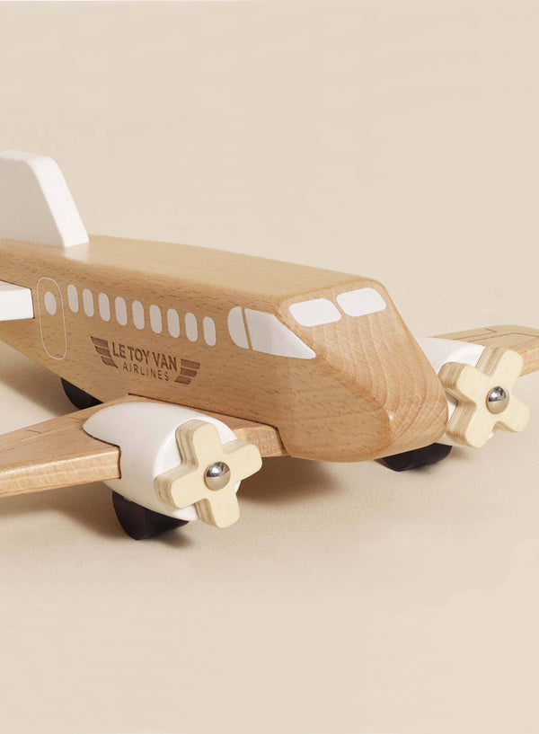 The Wooden Toy Plane is made from FSC-certified wood, painted light brown and white with windows, wings, and twin front propellers. "Le Toy Van Airlines" is printed on the side. This toy is charming and plastic-free.