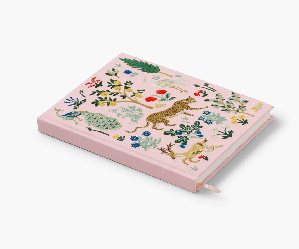 The Menagerie Embroidered Sketchbook is a pink hardcover journal with colorful floral embroidery, including peacock, leopard, and foliage designs, and features a handy ribbon bookmark.