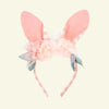 The Embellished Gingham Bunny Headband features a pink bunny ear design with a checkered pattern, pastel pink organza flowers, white blooms, and green leaves on a plain white backdrop.