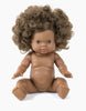 The Minikane Sitting Doll (13") - Charlie, featuring curly hair and brown skin, sits upright in detailed realism, proffering a gentle expression with blue eyes. This anatomically correct doll is unclothed and lifelike, emitting a delicate vanilla scent against a white backdrop.