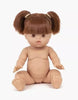 The Minikane Baby Doll Raphaelle with Dress is anatomically correct, featuring brown hair styled in pigtails and bangs. This 13" doll has a vanilla scent, visible joints at arms and legs, a neutral expression, and sleeping eyes. It's sitting upright against a plain white background.