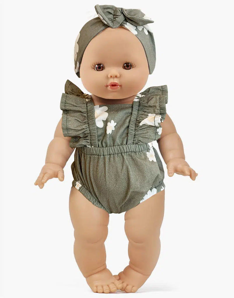 The Minikane Doll (13") - Faustine with Green Romper wears a matching headband, encouraging imaginative play. Crafted from phthalate-free vinyl, the doll has a neutral expression against a plain white backdrop.