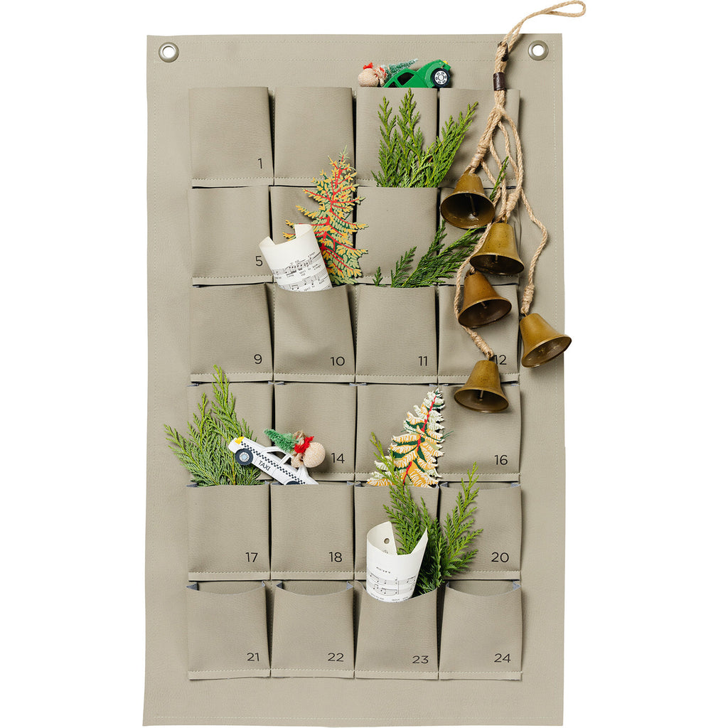 The Gathre Small Advent Calendar - Grove is a beautifully minimalist beige fabric advent calendar featuring 25 gift pockets filled with delightful surprises such as toy cars and sprigs of greenery. With bells elegantly suspended from the top right corner on a rope, this calendar adds a charming touch to your magical Christmas countdown.