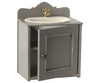A Maileg miniature sink in gray with a vintage metal tap, featuring an open door revealing internal shelves.