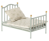 A Maileg Miniature Bed with a decorative headboard and footboard, holding a beige floral-patterned mattress and a matching pillow, isolated on a white background.