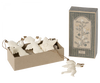 A decorative gift box containing the Maileg Holy Night Ornament Set, which includes white angel and star ornaments, rests next to its matching packaging labeled "Holy Night." These charming decorations are designed with gold hanging strings.