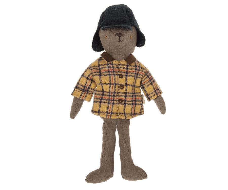 A plush toy bear, fondly called Teddy Dad, is dressed in a yellow plaid shirt, brown pants, and a dark blue hat with ear flaps. Each charming piece of the outfit is available for individual purchase under the product name "Maileg Extra Clothing: Woodsman Jacket and Hat for Teddy Dad." The bear stands proudly against a white background.
