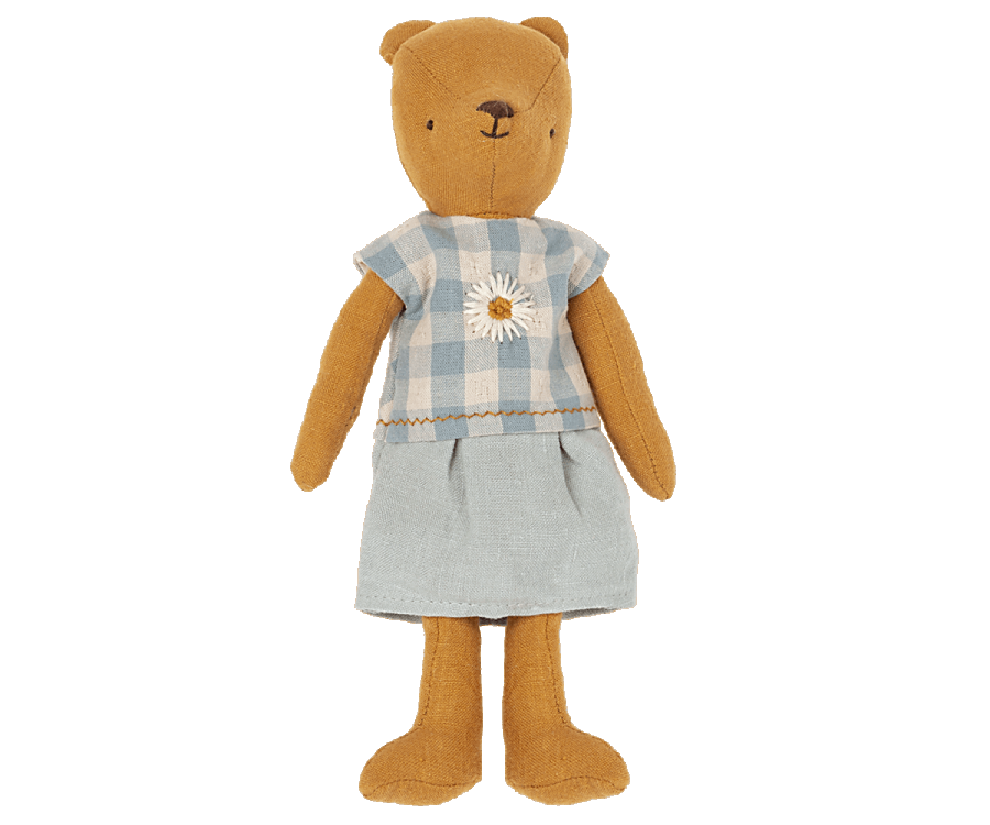 A Teddy Mum dressed in a charming blue and white checkered dress adorned with an embroidered sunflower. The stuffed bear stands upright with its arms at its sides and has a simple, stitched face with a small smile. Maileg Extra Clothing: Dress for Teddy Mum can be purchased separately.