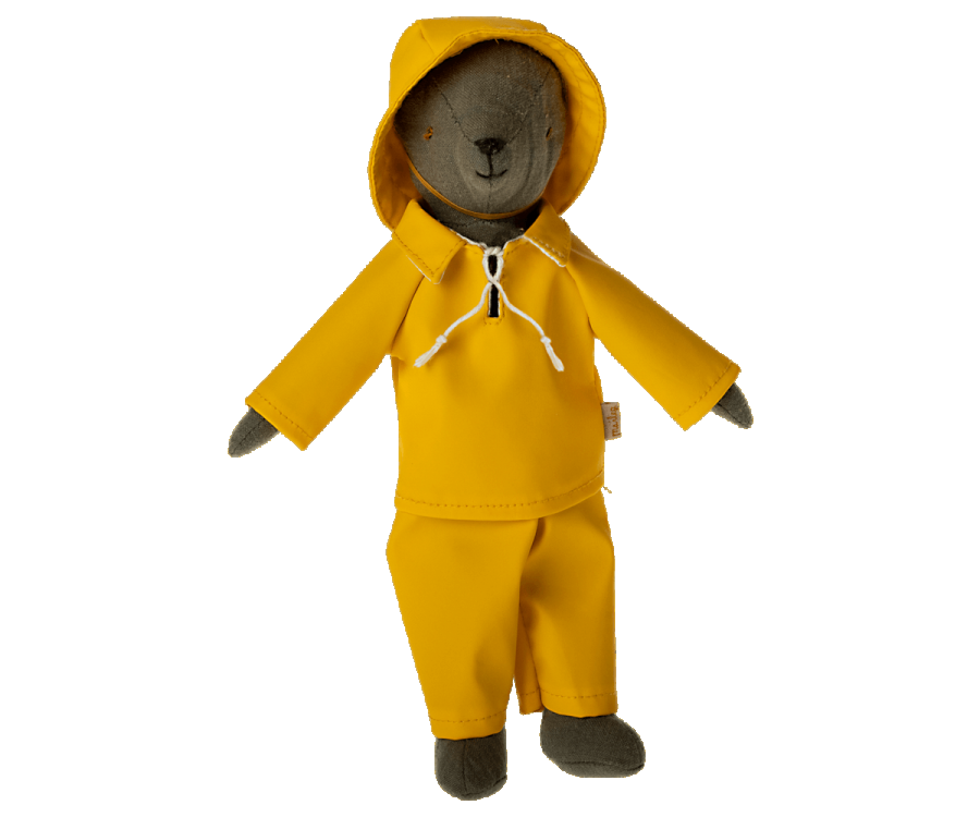 A toy bear, affectionately termed Teddy Dad, is dressed in the Maileg Extra Clothing: Rainwear for Teddy Dad—a charming ensemble featuring a yellow raincoat with a hood and matching yellow pants—as it stands upright.