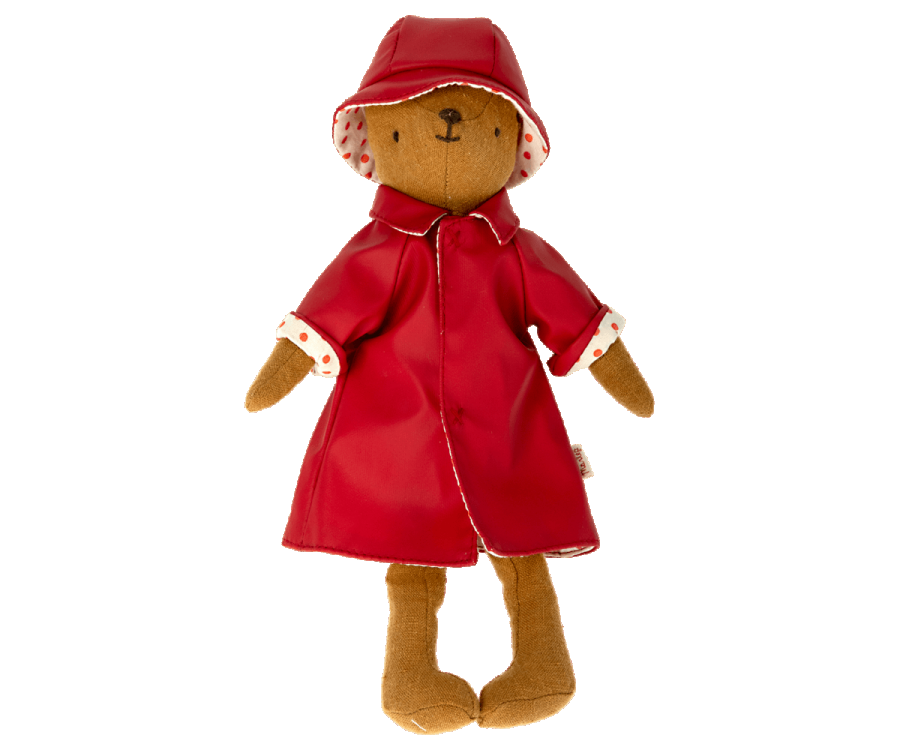 A brown teddy bear from the Teddy Mum collection is dressed in the Maileg Extra Clothing red raincoat with matching hat. The raincoat showcases white polka-dot lining on the sleeves. Featuring a simple embroidered face with black eyes and a tiny brown nose, this charming outfit makes for an adorable listing.
