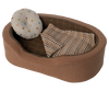 A toy dog bed with a pillow and a blanket.