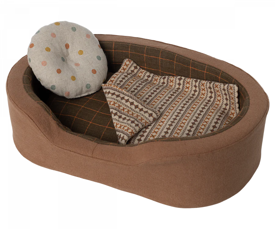 A toy dog bed with a pillow and a blanket.