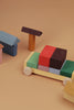 Raduga Grez Vehicle Blocks, crafted from solid wood and painted with eco-friendly colors, form a racing car using red, black, and green blocks on a beige surface, while the houses feature pink, blue, and yellow hues.