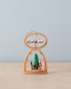 The Richard Glaesser Mini Pyramid Hanging Ornament - Santa features a German-made small wooden arch with stars, showcasing a Santa, green tree, and reindeer. It has a delicate propeller and handy hanging string against a soft blue background.