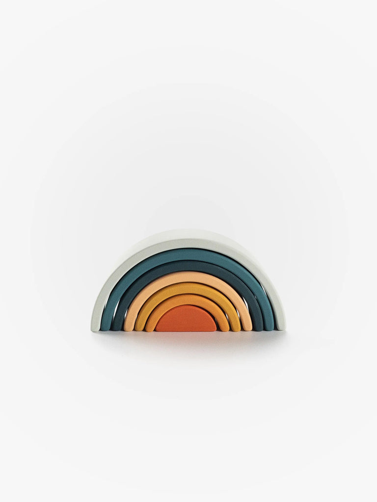 A stack of Handmade Mini Rainbow Stacker - Lagoon in shades of blue, gray, and orange arranged in a semicircular shape, resembling a rainbow, against a plain white background.
