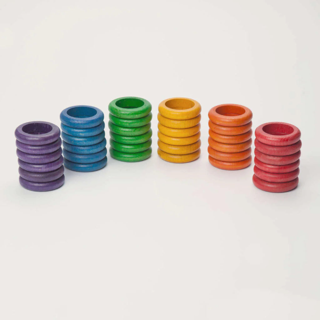 Five stacks of colorful Grapat 36 Rings in 6 Colors are arranged in a line on a white background, featuring purple, blue, green, orange, and red colors. Each stack varies in the number of rings.