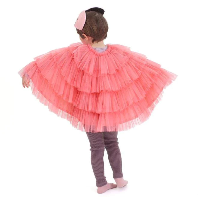A young girl in a Meri Meri Flamingo Costume and matching hairband stands with her back to the camera, looking over her shoulder, on a white background.