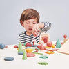 A young child engages in open-ended play with My Forest Floor, concentrating on stacking a piece. The background is light grey.