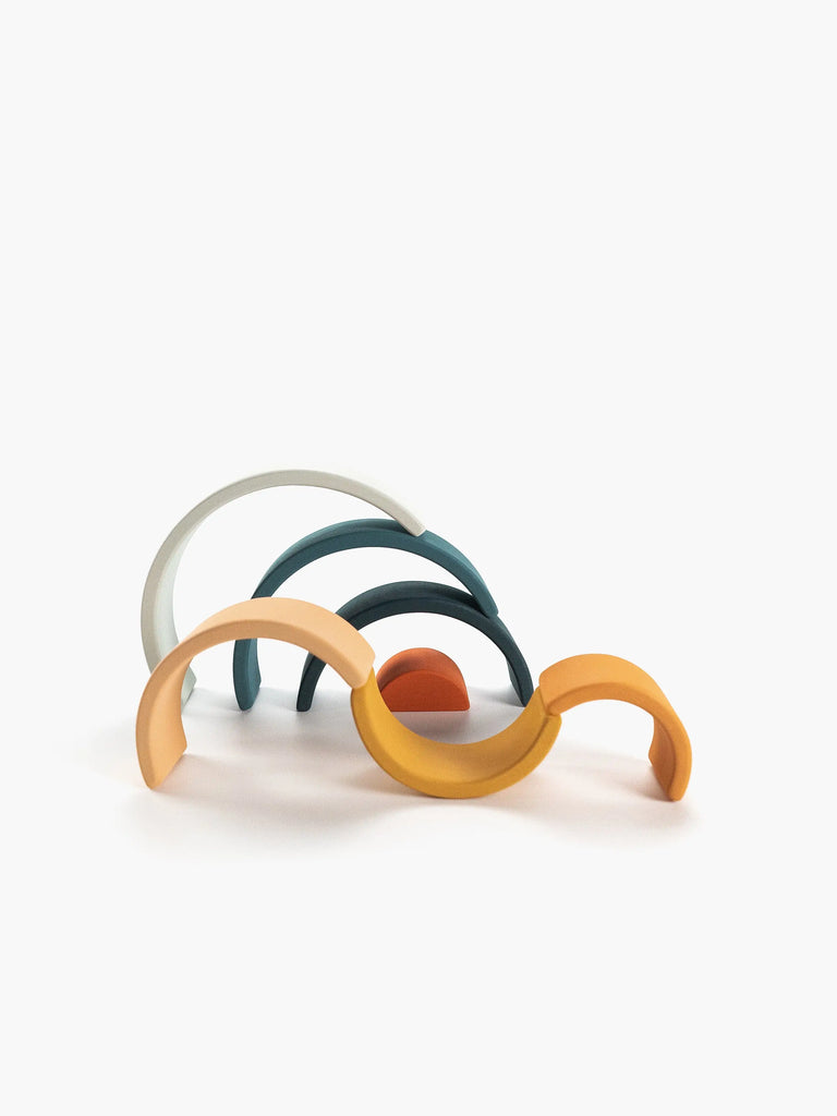 A collection of Handmade Mini Rainbow Stacker - Lagoon headbands laid out overlapping each other, with colors including orange, teal, gray, and bronze against a white background.