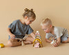 Two kids playing with  stacking toy with 7 pastel tone wooden arcs stacked into a rainbow shape. 