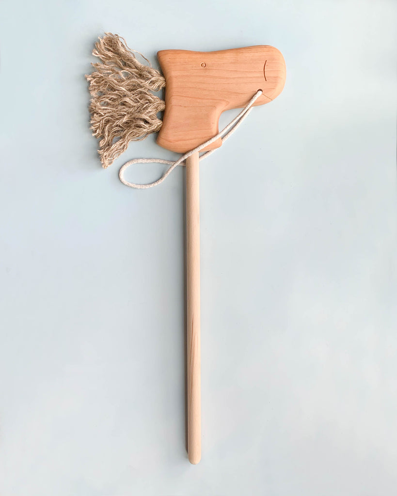The Handmade Wooden Riding Horse boasts a charming horse head on a stick, crafted from smooth beech wood and adorned with a string mane against a light background.