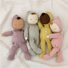 Four soft dolls with different skin tones in pajamas under a gauze blanket. 